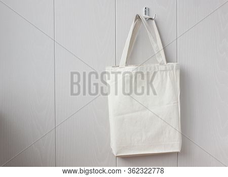 White Linen Bag Hanging On A Hook On A Light Wall. Space For Your Image Or Text. Eco Bag.