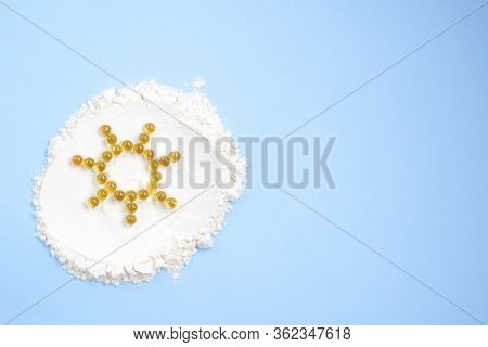 Vitamin D Yellow Pills In The Shape Of Sun On White Lecitin Powder In Sky Blue Background, Nutrition