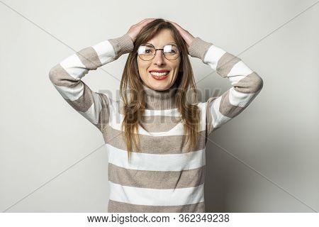 Portrait Of A Young Friendly Woman In A Striped Sweater And Glasses, Smiling And Pulling Hands On He