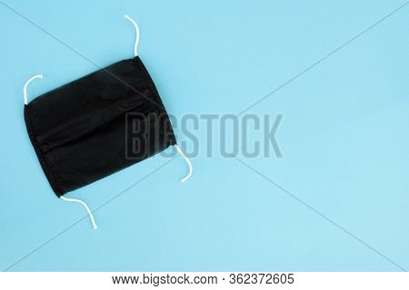 Black Face Protection Handemade Mask On Blue Background. Pandemic Or Epidemic Concept. Copy Space.