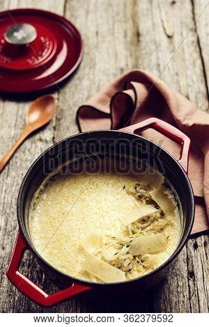 Creamy Polenta With Baked Onion And Cheese In Cast Iron Pot On Rustic Wooden Background. Italian Foo