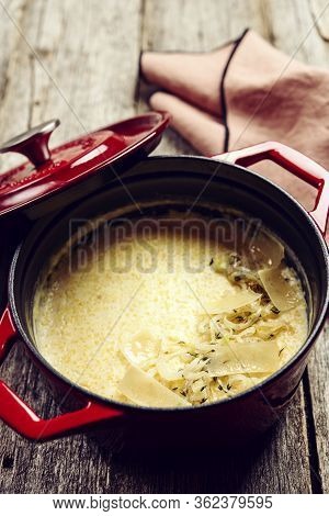 Creamy Polenta With Baked Onion And Cheese In Cast Iron Pot On Rustic Wooden Background. Italian Foo
