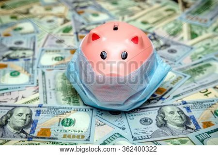 Piggy Bank In A Mask On A Background Of American Currency.the Concept Of Coronavrius Epidemic