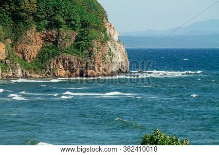 Seascape, Beautiful View Of The Rocky Cliff In The Sea With Mountains On The Horizon