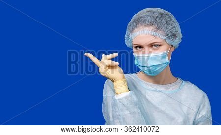 A Young Doctor In A Medical Uniform Points To A Poster. Space For Your Text. Medical Design Concept.
