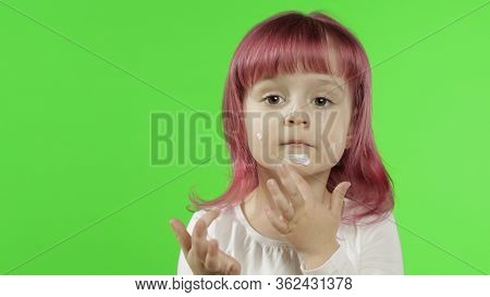 Beauty Caucasian Child Girl Model With Pink Hair Using Cream. Close Up. Puts Cream On Her Face Touch