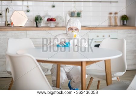 Woman In White Workwear And Protective Gloves Doing Disinfection In The Kitchen
