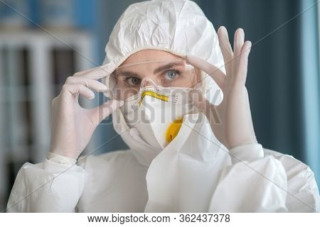 Woman In White Workwear Putting On Protective Eyewear
