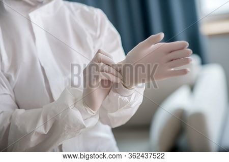 Person In White Workwear Wearing Protective Gloves Before Disinfection