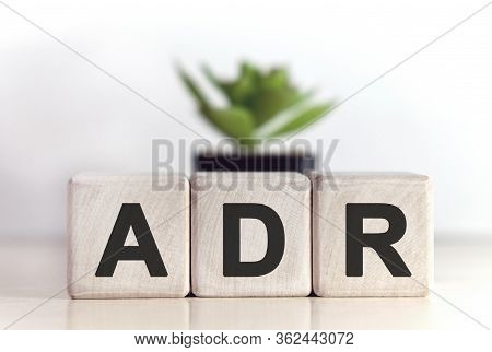 Adr Concept On Wooden Cubes And Flower In A Pot In The Background