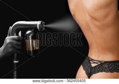 Woman Body Paint Instant Tan Spray Skintone With Airbrush In Professional Beauty Salon On Black Back