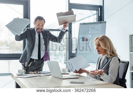 Confused Businesswoman Holding Petition To File To Bankruptcy Near Cheerful Businessman Holding Docu