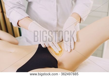 Bikini Depilation Waxing. The Master Makes Hair Removal In The Salon