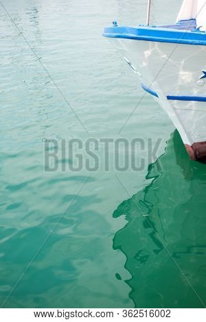 Ship's bow and aquamarine water in the port of Syracuse, Sicily. Boat and sea, detail. Sailing vessel drops anchor in a quiet bay
