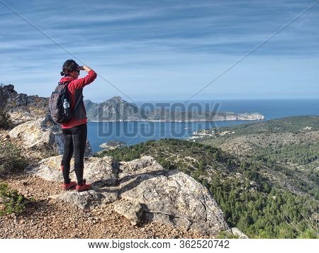 Nice Black Hair Gilr Is Watching From  Pintal Vermell Peak Trail The Sant Elm Village And Sa Dragone