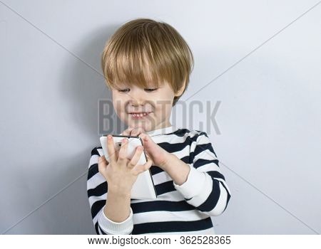 Little European Child Blond Child Plays, Looks At The Smartphone Cell Phone And Rejoices Smiling Lau