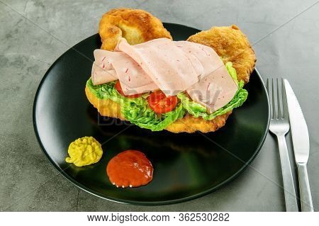 Navajo Bread, Taco With Tomotoes, Green Lettuce, Ham And Sauce On The Black Plate, Cutlery On The Da