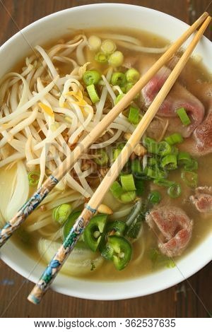 Asian noodle soup with beef, shives, onion, bean sprout and lime