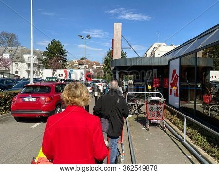 Paris, France - Mar 21, 2020: Rear View Of People In French Auchan Supermarket Robertsau Queue Keepi