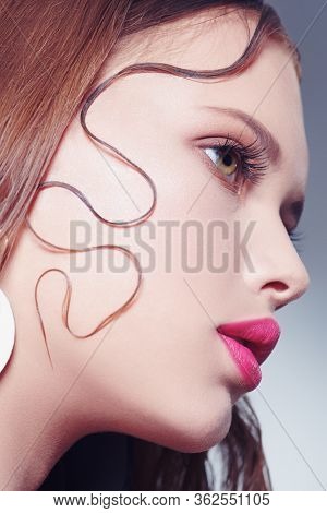 Beauty portrait, hair styling. Close-up of a beautiful young woman with fresh shining make-up and refined elegant hairstyle.