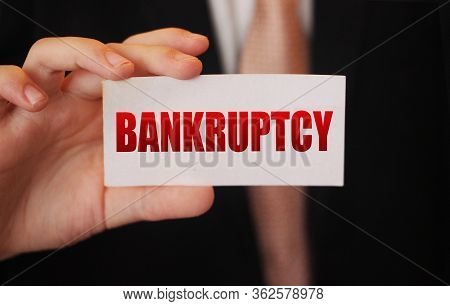 Bankruptcy On A Card. Businessman Holding A Card With Word Bankruptcy. Crisis Business Closing Debts