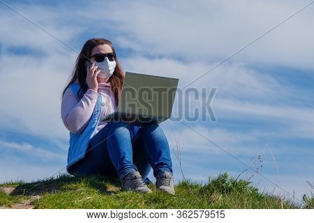 A Business Woman Speaks On Phone On Street In Medical Mask During Coronavirus Pandemic Against Backg