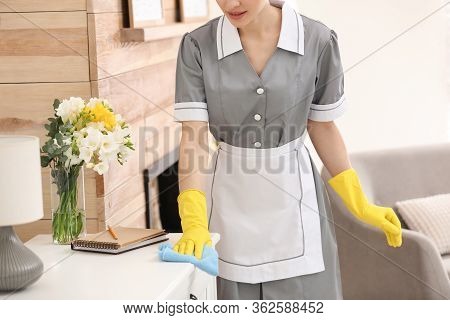 Young Chambermaid Wiping Dust From Furniture In Hotel Room, Closeup