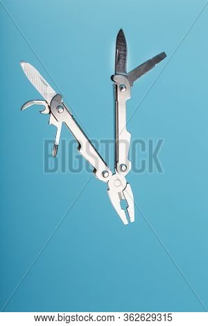 The Multitool Multi-function Tool Hovers On A Blue Background. The Concept Of An Expanded Multi-tool