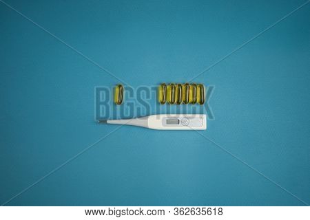 Electronic Thermometer With A Flexible Tip And Vitamins On A Blue Background