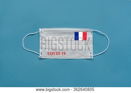 Medical Mask With The Flag Of France And The Inscription Covid-19 On A Blue Background