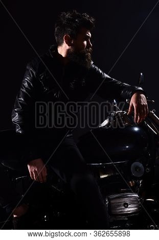 Man With Beard, Biker In Leather Jacket Lean On Motor Bike In Darkness, Black Background. Macho, Bru