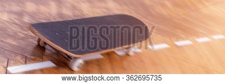 Old Skateboard Located On Brown Wooden Parquet Boards With White Lines At Bright Summer Sunlight Clo