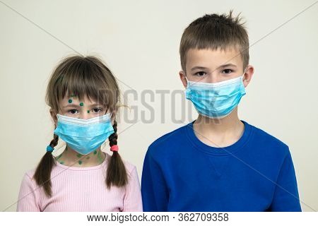Boy And Girl Wearing Blue Protective Medical Mask Ill With Chickenpox, Measles Or Rubella Virus With