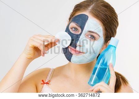 Woman With Clay Carbo Black Mask On One Half Face And White Mud On Second Half. Girl Removing Cosmet
