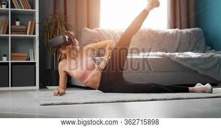Slim Girl In Vr And Activewear Side-lying On Floor Raising One Leg Up Doing Fitness Exercises In Apt
