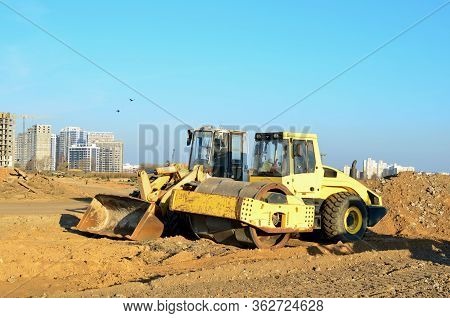Soil Compactor And Wheel Loader At Construction Site. Vibration Single-cylinder Road Roller Leveling