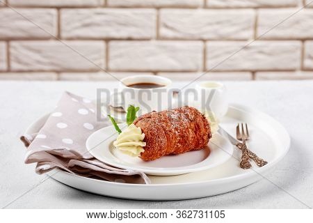Czech Pastry Trdelnik Filled With Cream Decorated With Mint, Served On A White Dessert Plate, With C