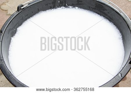 Soapy Water In A Black Bucket. Suds And Soapy Water. A Bucket Of Soapy Water