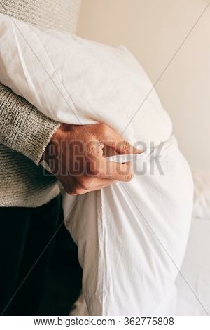 closeup of a young caucasian man introducing a pillow into a white pillow case as he is making the bed