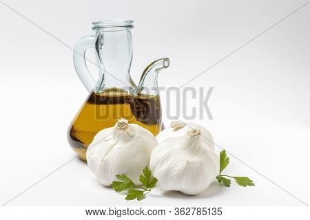 Horizontal View Of An Oil Pourer With Olive Oil, Three Head Of Garlic And Leaves Of Parsley Isolated
