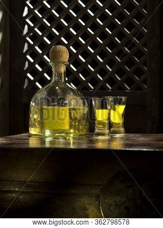Close Up View Of Bottle Of Tequila Anejo And Glasses On Color Background