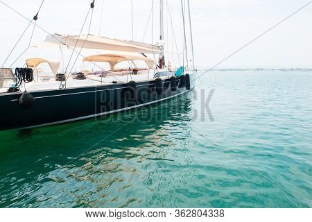 Ship's bow and aquamarine water in the port of Syracuse, Sicily. Boat and sea, detail. Sailing vessel drops anchor in a quiet bay