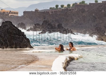 Porto Moniz Madeira - August 2, 2018: Girls Bathes In A Natural Lava Pool During High Tides And Larg