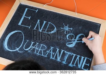 Close Up Of Female Hand Writing The Lettering End Of Quarantine On Chalkboard With Blue Chalk And Or