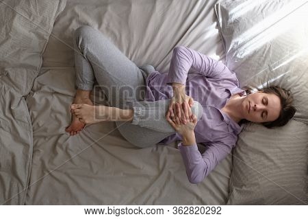 Woman Lying On Bed In The Morning And Doing Stretching Exercise From Yoga