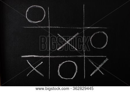 Top View Of Tic Tac Toe Game On Blackboard With Chalk Grid, Naughts And Crosses