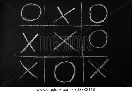 Top View Of Tic Tac Toe Game On Blackboard With Chalk Grid, Naughts And Crosses