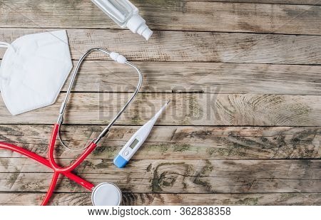 Red Stethoscope, Mask Kn 95, Thermometer And Sanitizer On Rustic Wooden Background. Top View Wiyh Co