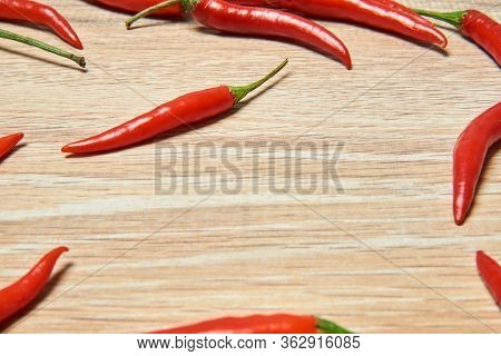 Background - Pods Of Red Chili Pepper Form A Kind Of Frame On A Wooden Surface
