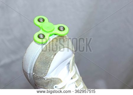 Green Spinner On The Foot Shod In Sneakers. Pastime.